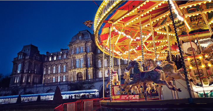 view of Bowes Museum with market stalls and fair ground ride outside for Christmas market